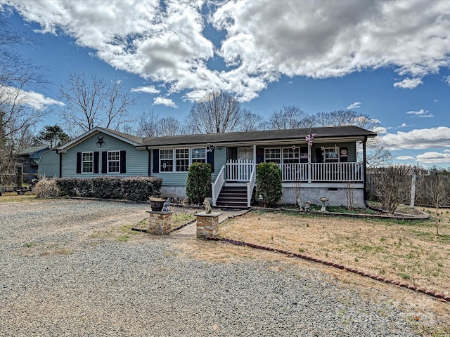 ranch-style home featuring gravel driveway and a porch