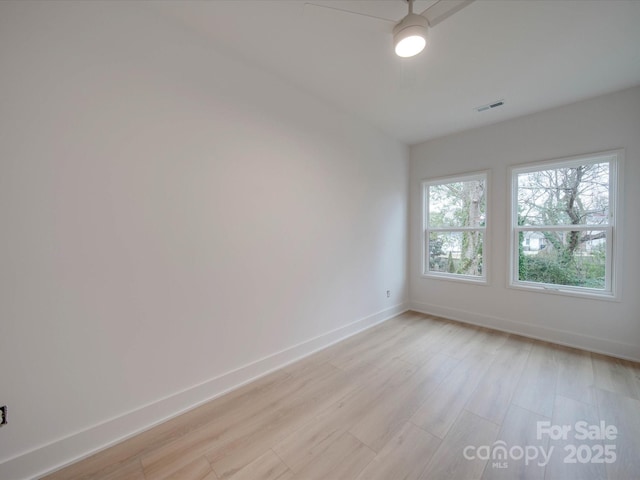 empty room with visible vents, light wood finished floors, and baseboards