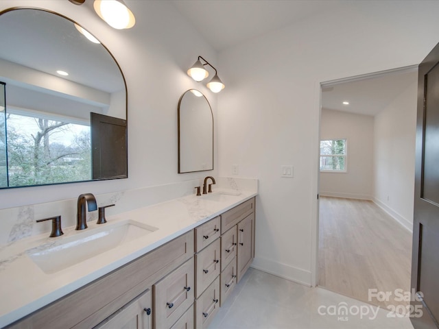 bathroom featuring double vanity, a sink, and baseboards