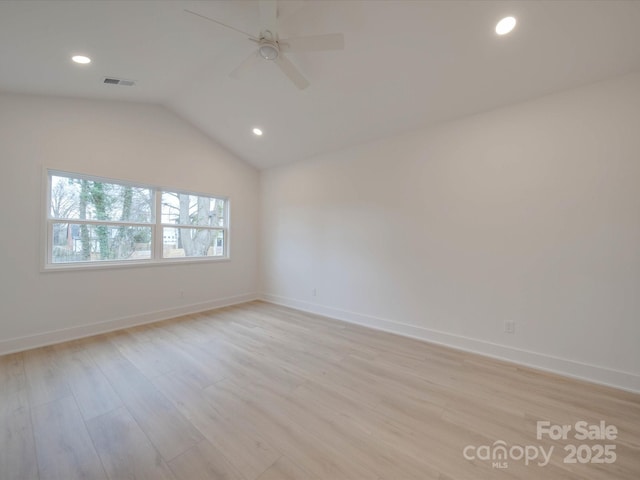 spare room with lofted ceiling, ceiling fan, visible vents, baseboards, and light wood-style floors