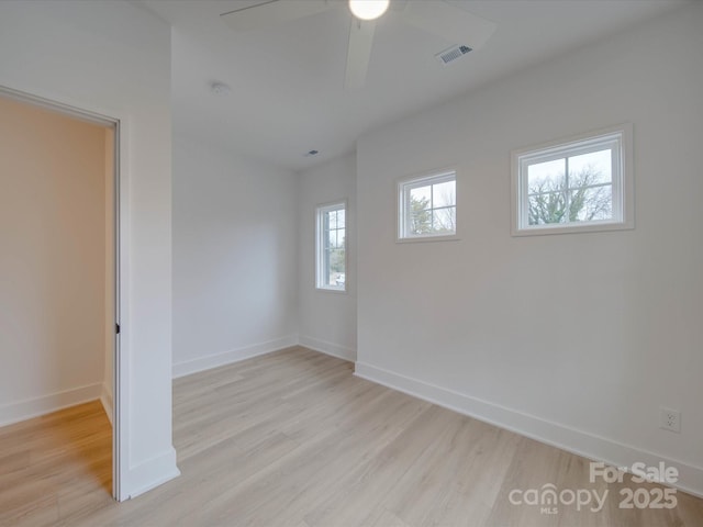 spare room with baseboards, a ceiling fan, visible vents, and light wood-style floors