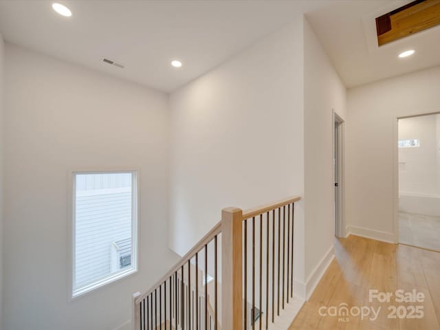 corridor featuring recessed lighting, visible vents, light wood-style flooring, an upstairs landing, and baseboards