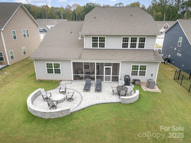 rear view of property featuring a patio area, a lawn, roof with shingles, and a sunroom