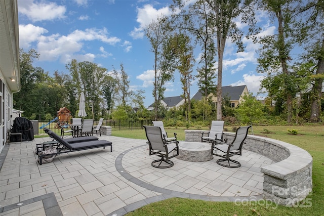 view of patio / terrace featuring a playground, a fire pit, and fence