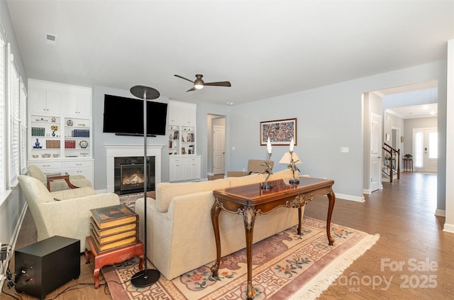 living area featuring visible vents, ceiling fan, stairs, light wood-style flooring, and a fireplace