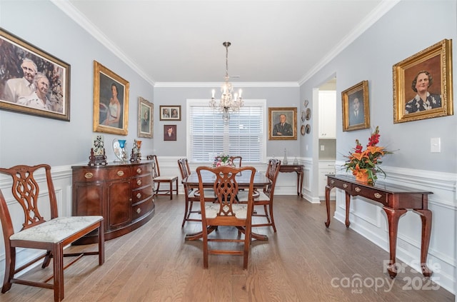 dining space with a notable chandelier, wood finished floors, and a wainscoted wall