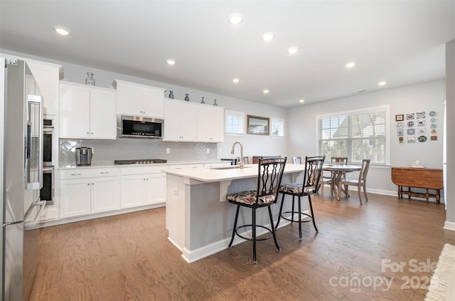 kitchen with light wood-style flooring, a kitchen island with sink, appliances with stainless steel finishes, and a sink