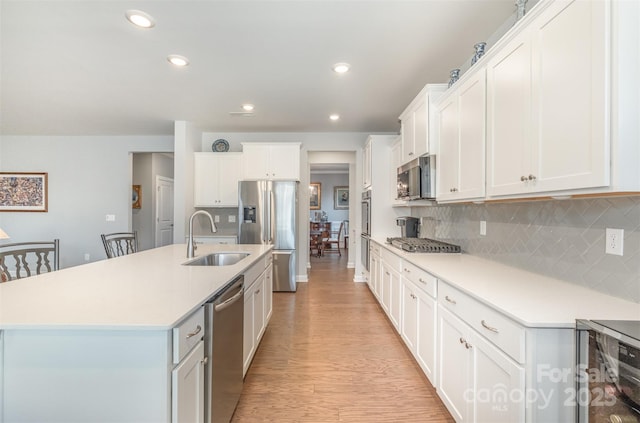 kitchen with a center island with sink, a sink, wine cooler, appliances with stainless steel finishes, and light wood-type flooring