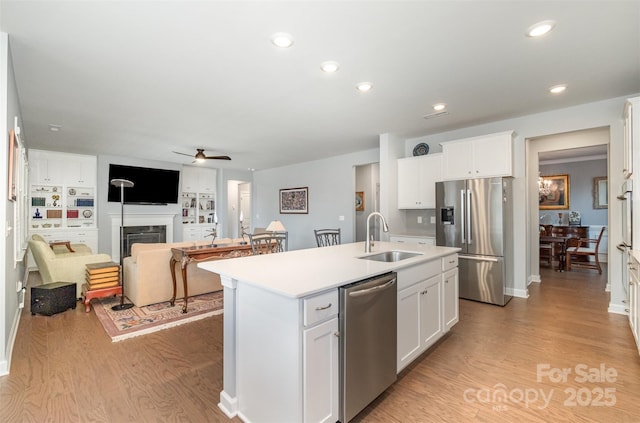 kitchen featuring a sink, stainless steel appliances, light wood-type flooring, and a kitchen island with sink