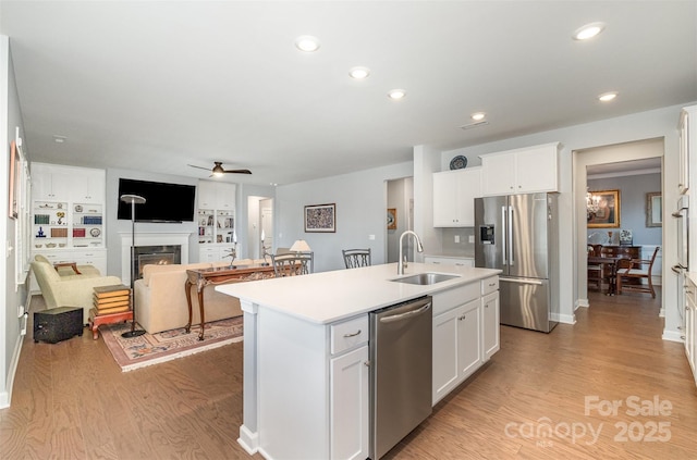 kitchen featuring a sink, light wood-style floors, appliances with stainless steel finishes, and an island with sink