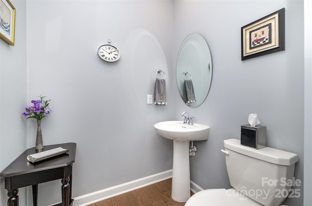 bathroom with toilet, wood finished floors, and baseboards