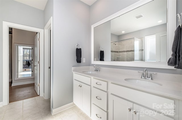 bathroom with tile patterned flooring, a shower stall, double vanity, and a sink