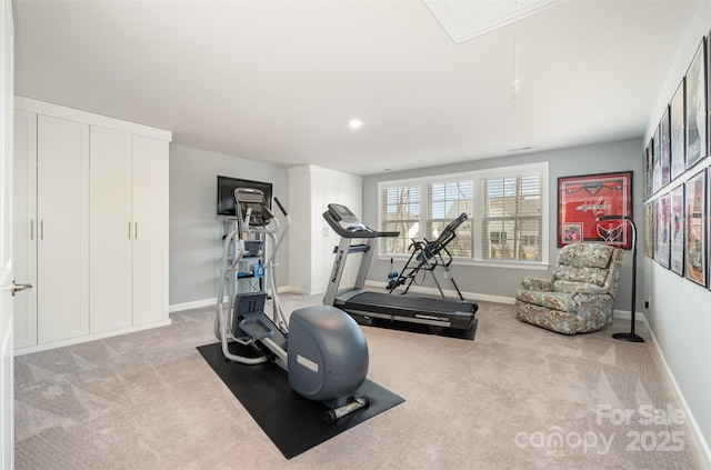 exercise room featuring carpet flooring, attic access, and baseboards