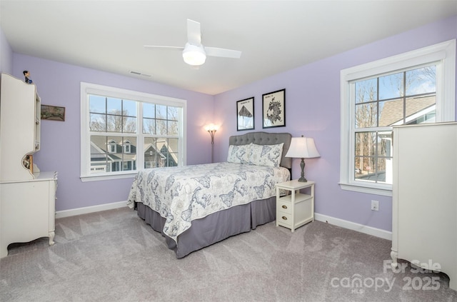 carpeted bedroom with visible vents, multiple windows, baseboards, and ceiling fan