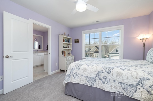 bedroom with visible vents, connected bathroom, baseboards, light carpet, and a sink