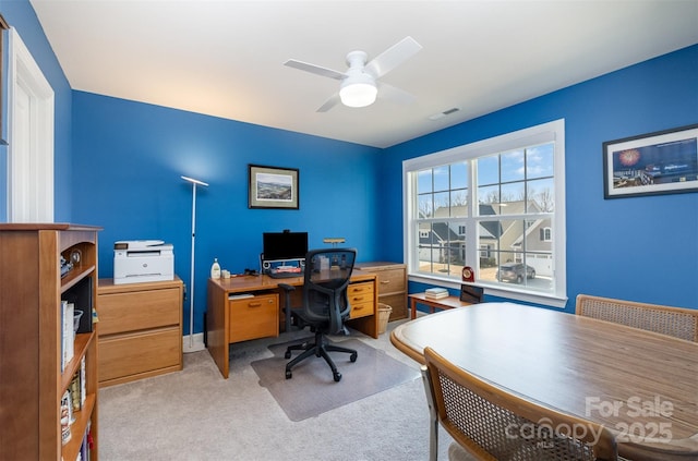 office space with a ceiling fan, visible vents, and light carpet