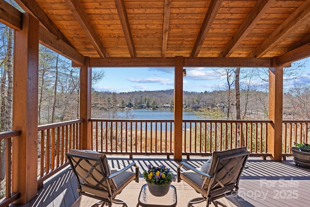 deck with a water view and a wooded view