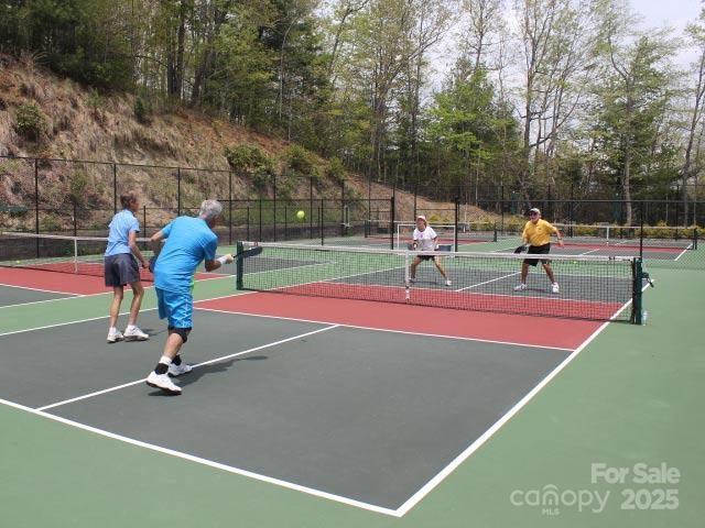 view of tennis court featuring community basketball court and fence