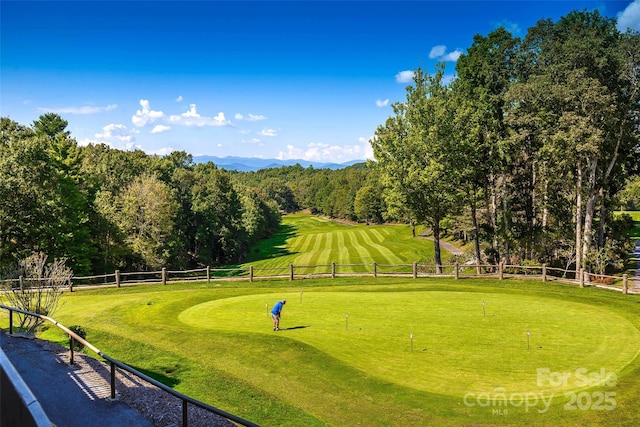 view of home's community with a lawn, golf course view, and fence