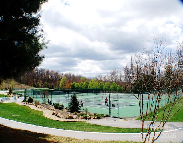 view of tennis court featuring a yard and fence