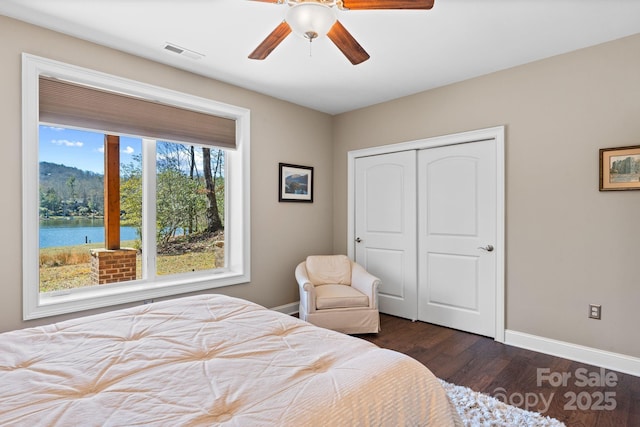 bedroom featuring dark wood-style floors, visible vents, baseboards, ceiling fan, and a closet