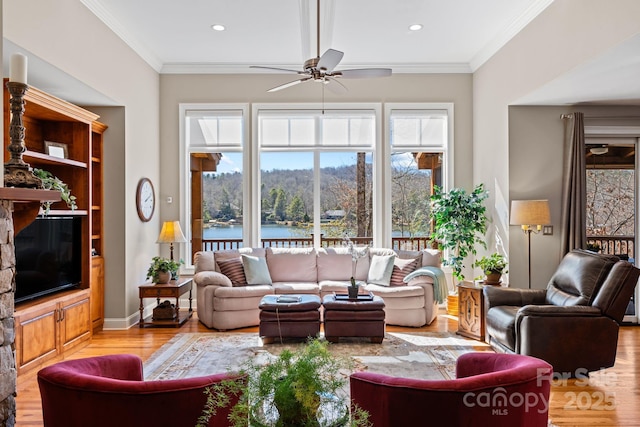 living room featuring baseboards, a water view, ceiling fan, ornamental molding, and light wood-style floors