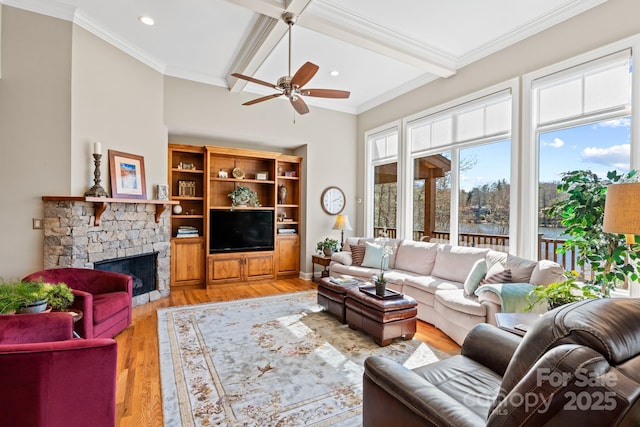 living room featuring beamed ceiling, a stone fireplace, light wood-type flooring, and ceiling fan