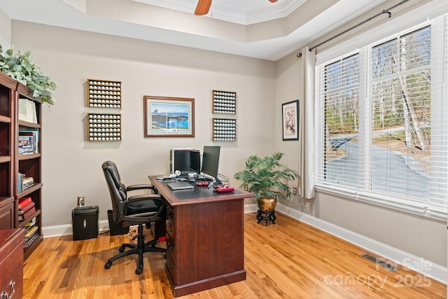 office area featuring a tray ceiling, light wood-style floors, baseboards, and ceiling fan