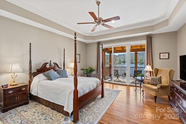 bedroom with light wood-type flooring, a ceiling fan, access to outside, a tray ceiling, and crown molding