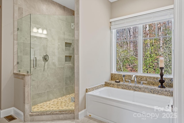 bathroom featuring a shower stall, baseboards, and a garden tub