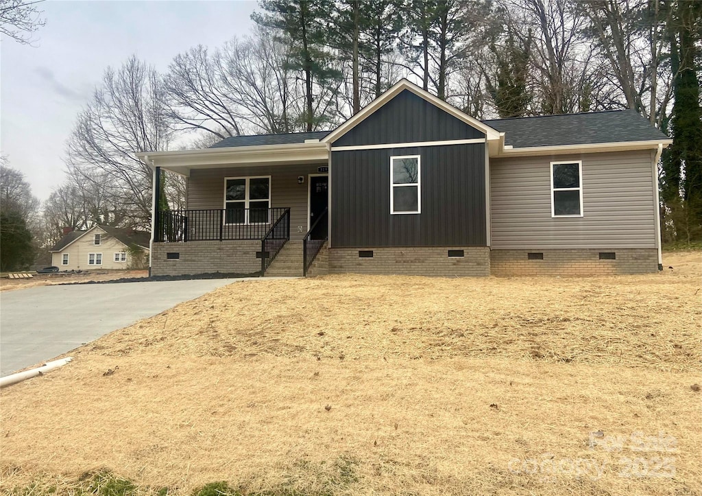 view of front of home with crawl space, covered porch, and roof with shingles