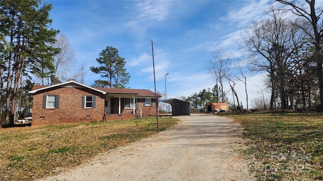 view of front facade featuring crawl space, driveway, brick siding, and a carport