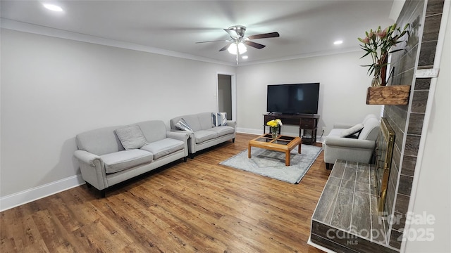 living room with ceiling fan, crown molding, baseboards, and wood finished floors