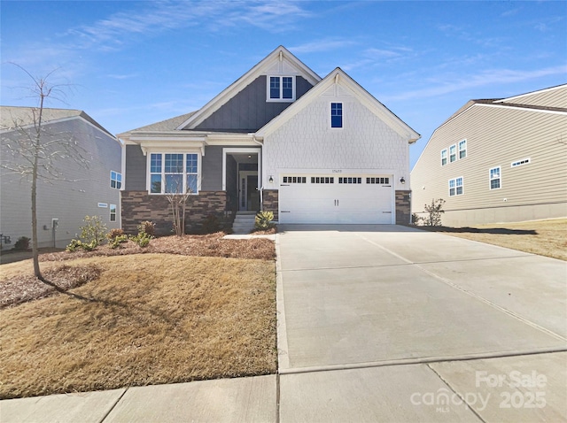 view of front of house featuring a garage, stone siding, board and batten siding, and driveway