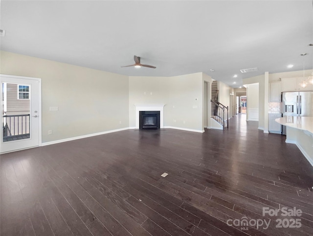 unfurnished living room with dark wood-style floors, visible vents, and a glass covered fireplace