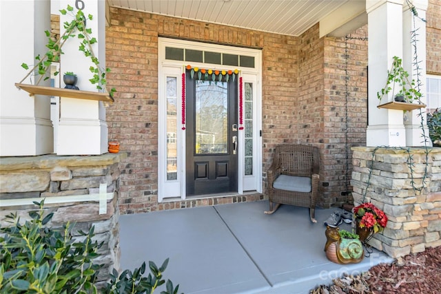 doorway to property with brick siding and covered porch