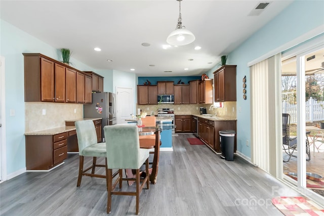 kitchen with wood finished floors, visible vents, a sink, appliances with stainless steel finishes, and a center island