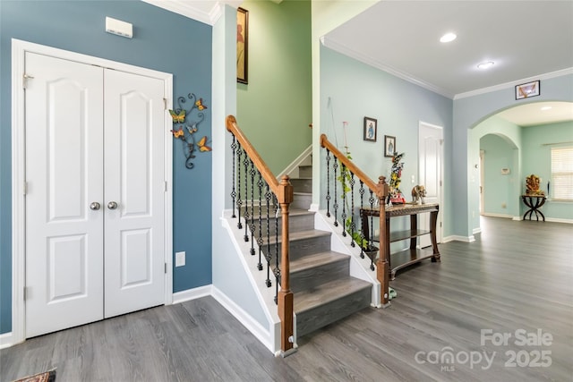 stairway with baseboards, ornamental molding, recessed lighting, wood finished floors, and arched walkways