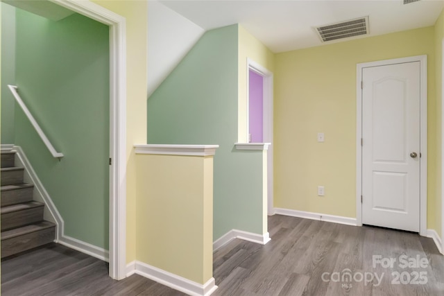 interior space featuring visible vents, baseboards, lofted ceiling, and wood finished floors