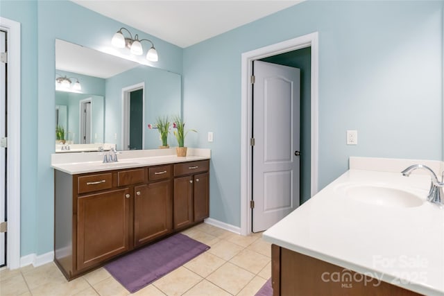 bathroom with tile patterned flooring, two vanities, baseboards, and a sink