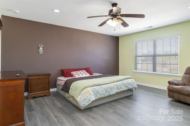 bedroom with ceiling fan, visible vents, baseboards, and wood finished floors