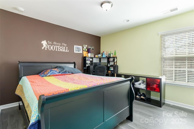 bedroom featuring visible vents, light wood-style flooring, and baseboards