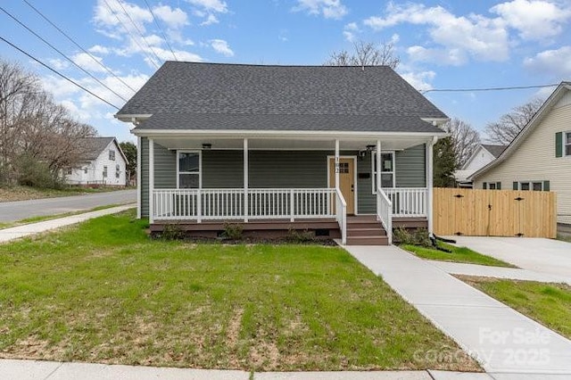 bungalow-style home with a front yard, covered porch, roof with shingles, and a gate