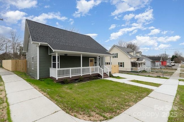 bungalow-style house featuring a shingled roof, fence, a porch, and a front yard