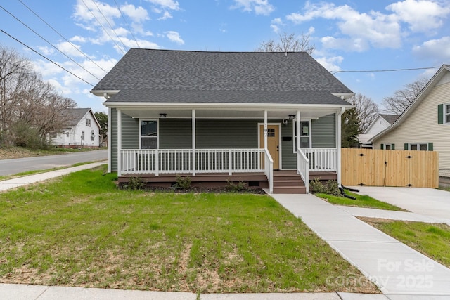 bungalow-style home featuring covered porch, a shingled roof, and a front lawn
