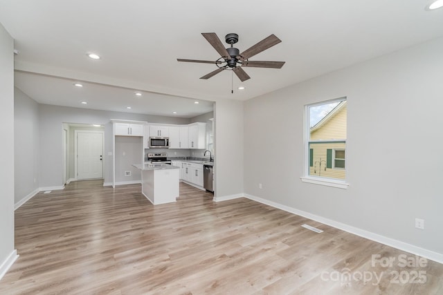 unfurnished living room with ceiling fan, a sink, baseboards, light wood-style floors, and recessed lighting