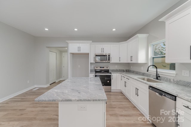 kitchen featuring light stone counters, a sink, a kitchen island, and stainless steel appliances