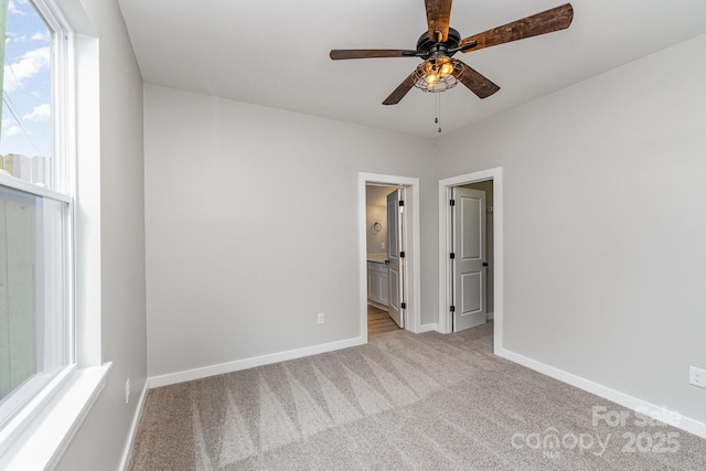 unfurnished bedroom with baseboards, ensuite bath, and light colored carpet