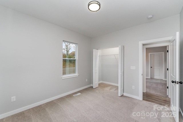 unfurnished bedroom with a closet, baseboards, carpet flooring, and visible vents