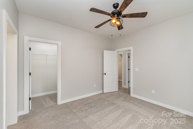 unfurnished bedroom featuring a walk in closet, baseboards, carpet, and a closet